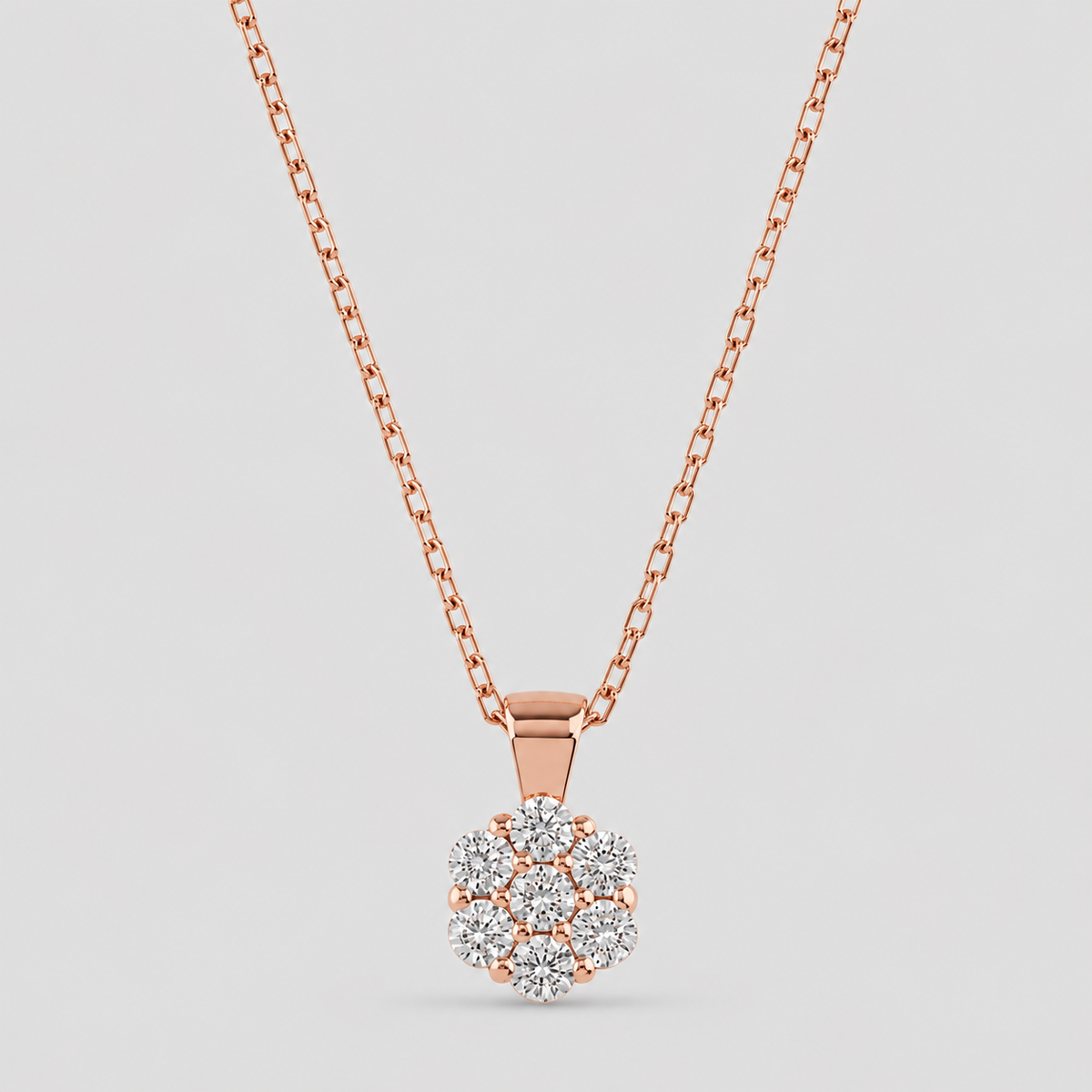 A rose gold necklace with a flower-shaped cluster pendant set with clear gemstones, shown against a light gray background.