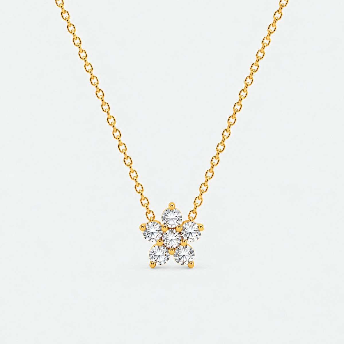 A delicate gold chain necklace with a small flower-shaped pendant set with clear round-cut gemstones, shown against a plain light gray background.
