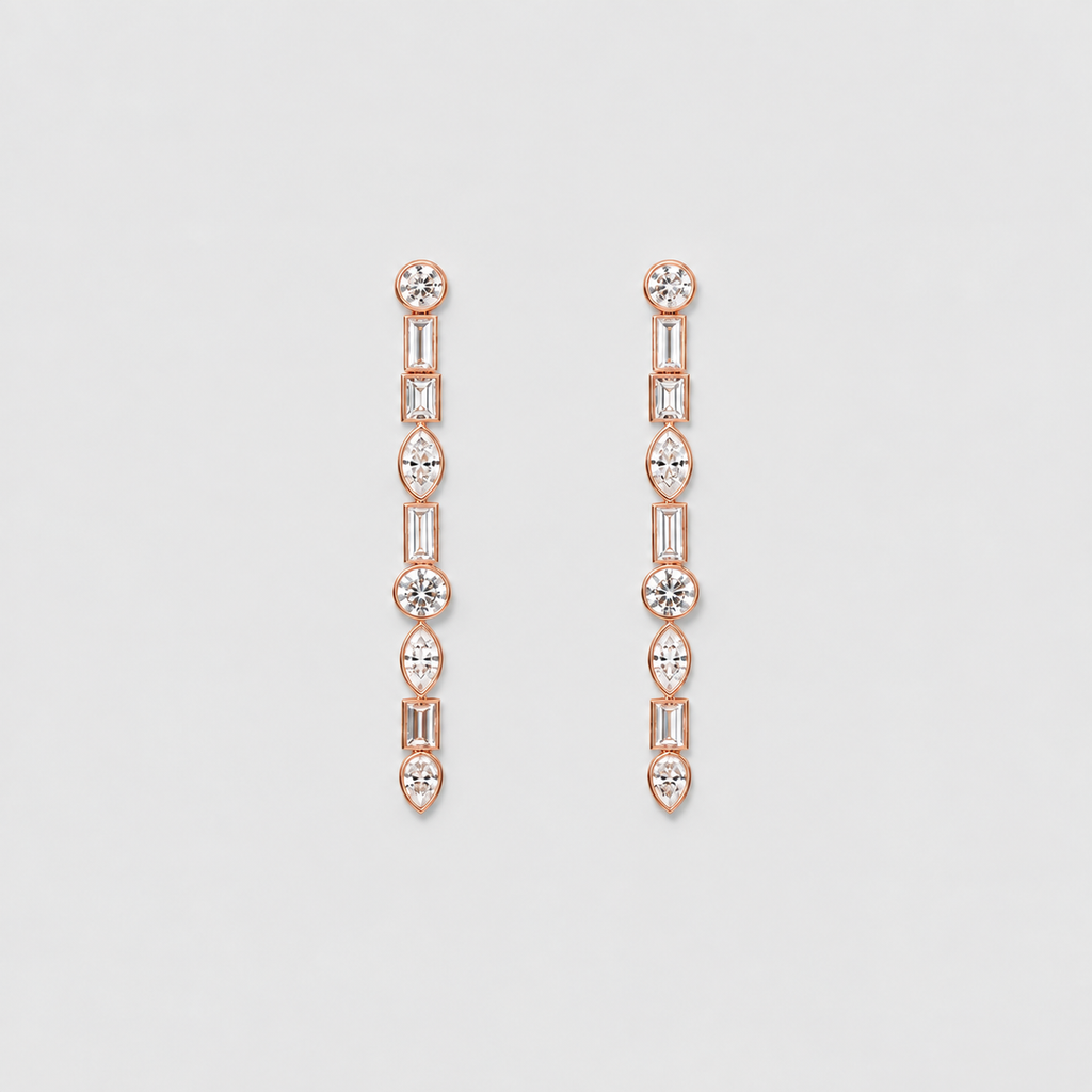 A pair of rose gold drop earrings featuring a vertical chain of baguette, round, and marquise-cut clear gemstones, displayed on a light gray background.