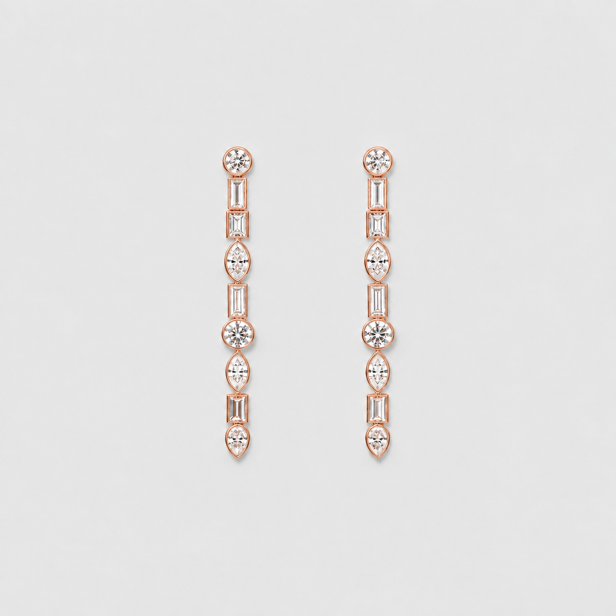 A pair of rose gold drop earrings featuring a vertical chain of baguette, round, and marquise-cut clear gemstones, displayed on a light gray background.