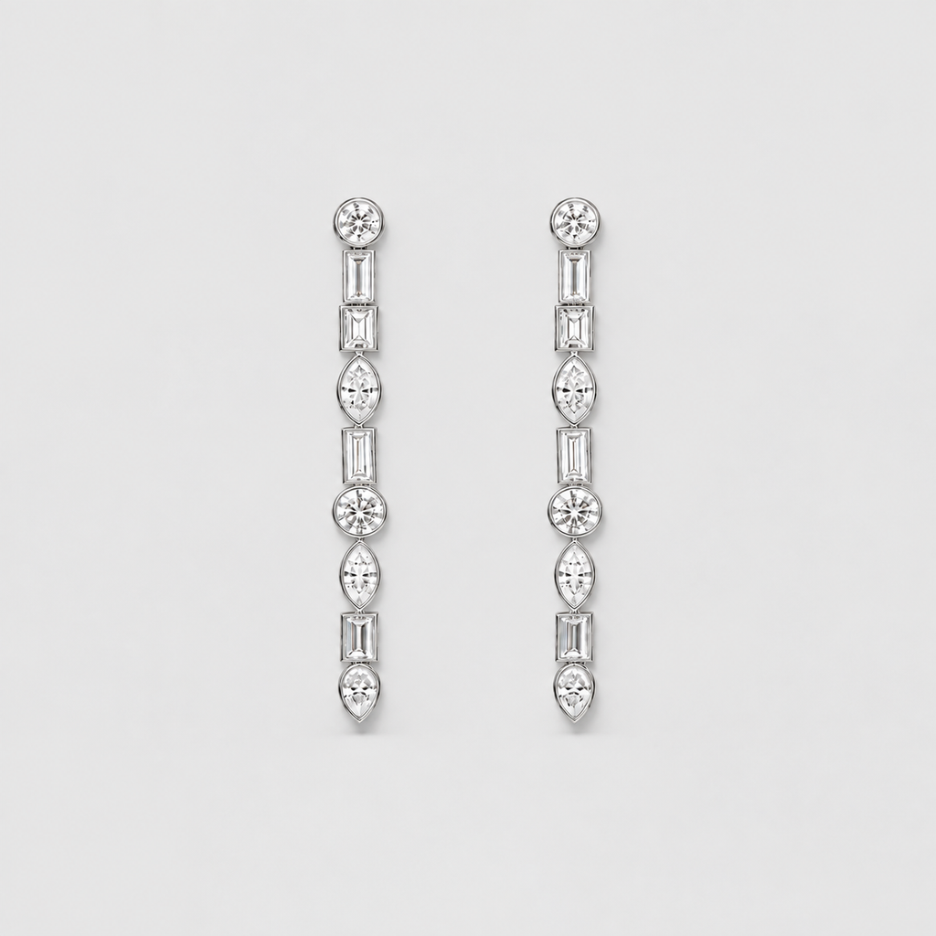 A pair of silver-toned drop earrings with a vertical arrangement of clear gemstones in round, baguette, and marquise shapes, set against a plain light gray background.