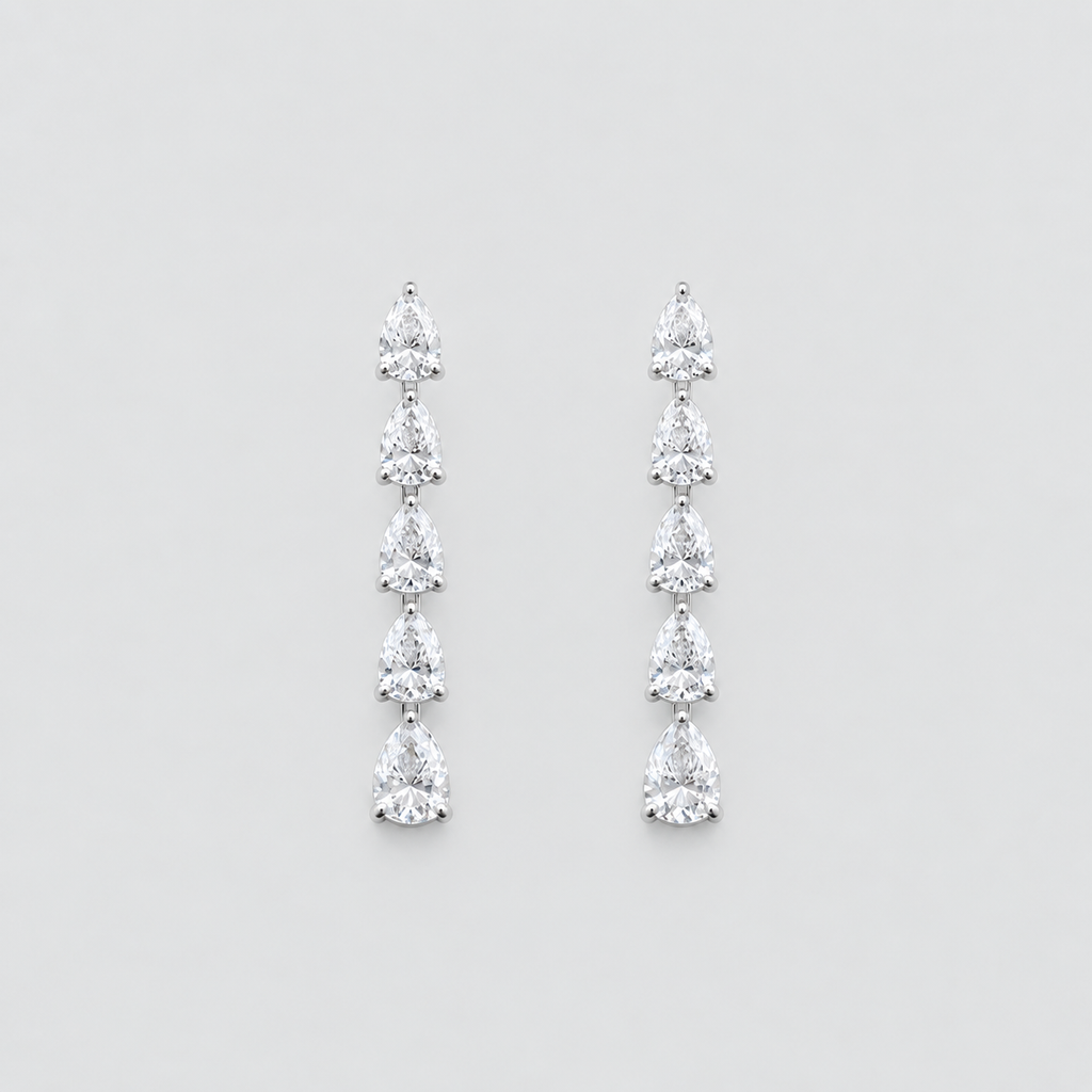A pair of silver drop earrings featuring a vertical arrangement of five pear-cut clear gemstones in a prong setting, displayed against a neutral light gray background.