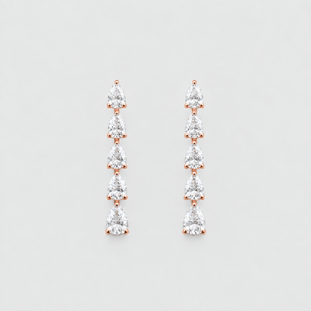 A pair of rose gold drop earrings featuring a vertical arrangement of seven pear-cut clear gemstones in a prong setting, displayed against a light gray background.