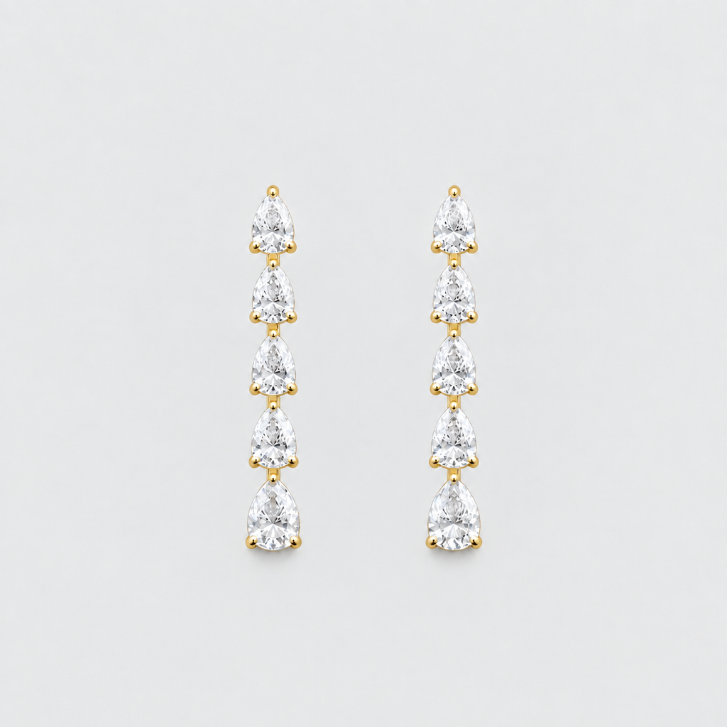 A pair of gold drop earrings featuring five pear-cut clear gemstones in a vertical dangle design, set against a solid light gray background.