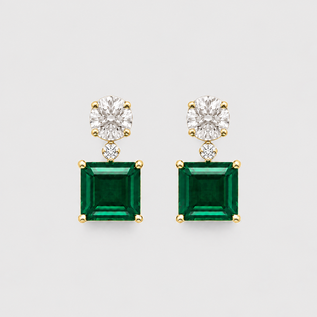 Pair of gold earrings with clear gemstones on a white background