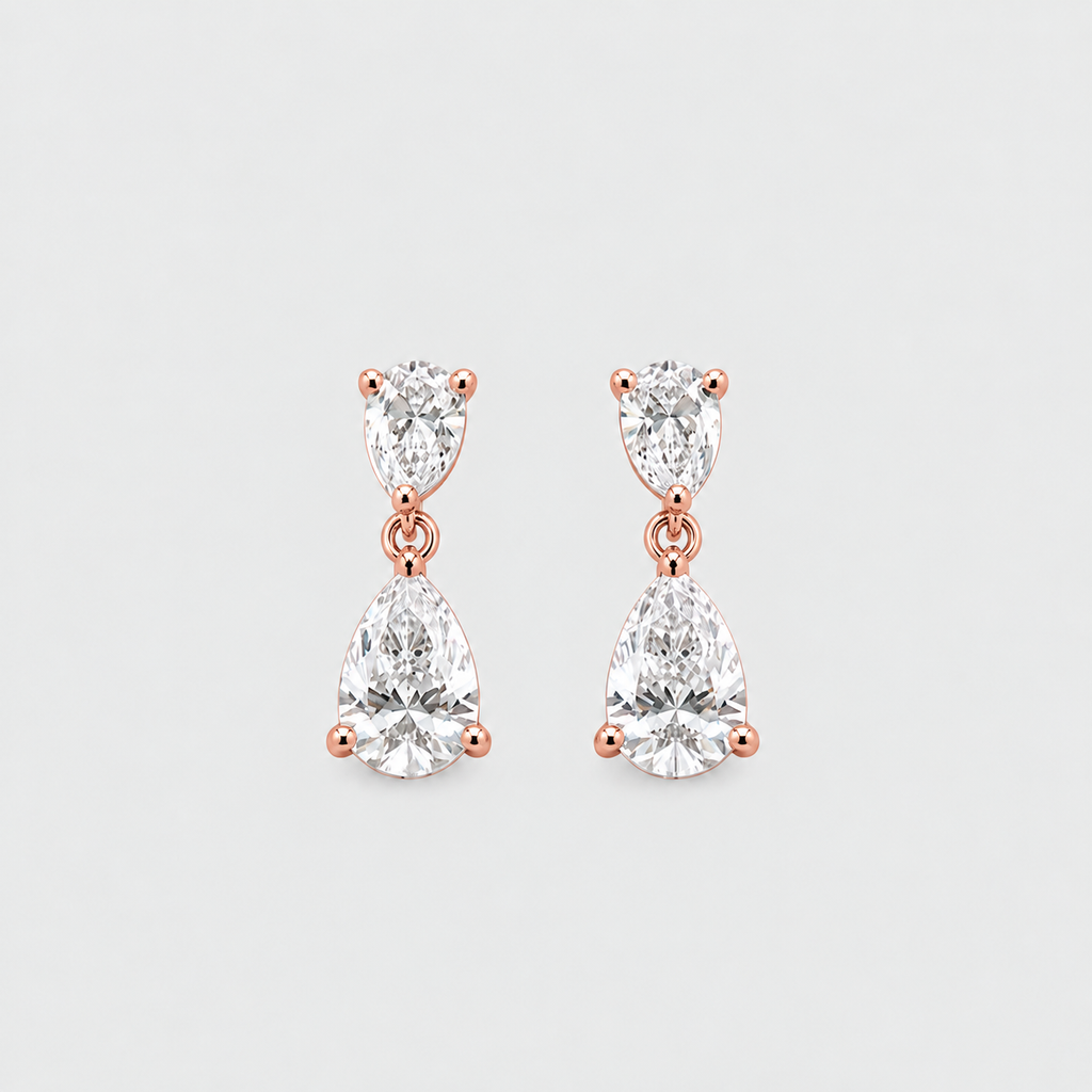 A pair of rose gold drop earrings featuring marquise-cut and pear-cut clear gemstones in a prong setting, displayed on a light gray background.