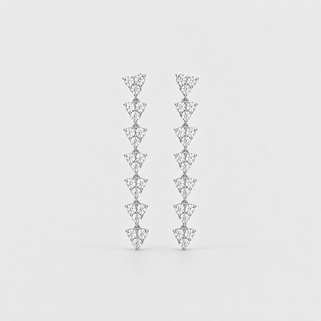A pair of silver-toned drop earrings featuring a vertical stack of small triangular pavé diamond clusters, set against a plain light gray background.
