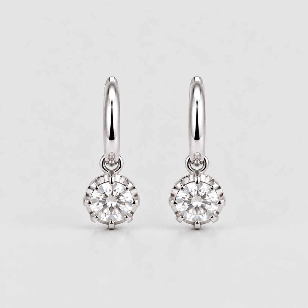A pair of silver hoop earrings with round-cut clear gemstones in a prong setting, displayed on a light gray background.