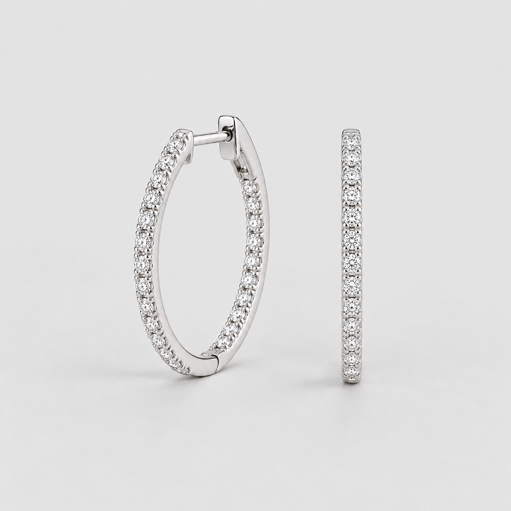 A pair of silver hoop earrings paved with small clear stones, shown from the front and side against a light gray background.