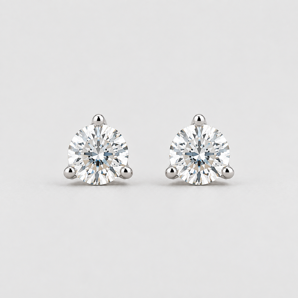 A pair of round-cut solitaire stud earrings in a silver-toned setting, displayed on a clean light gray background.