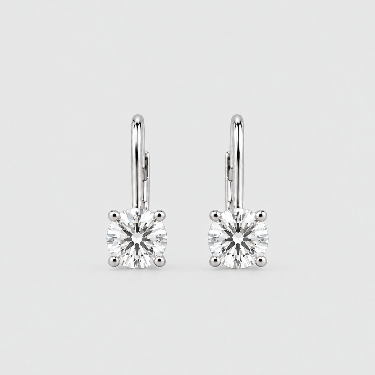 A pair of silver leverback earrings with square-cut clear gemstones in four-prong settings, shown on a light gray background.