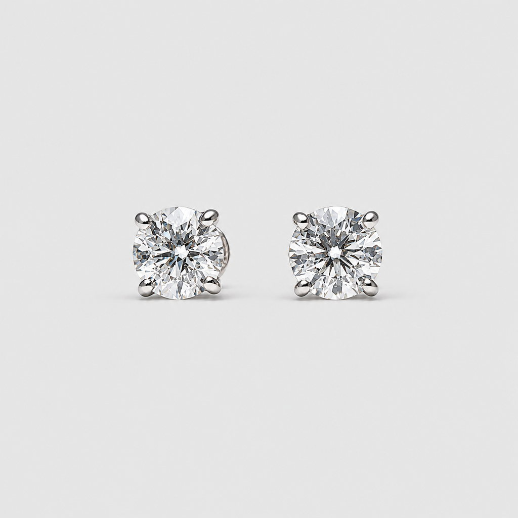 A pair of round-cut solitaire stud earrings in a silver-toned setting, displayed on a light gray background.