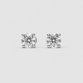 A pair of round-cut solitaire stud earrings in a silver-toned setting, displayed on a light gray background.