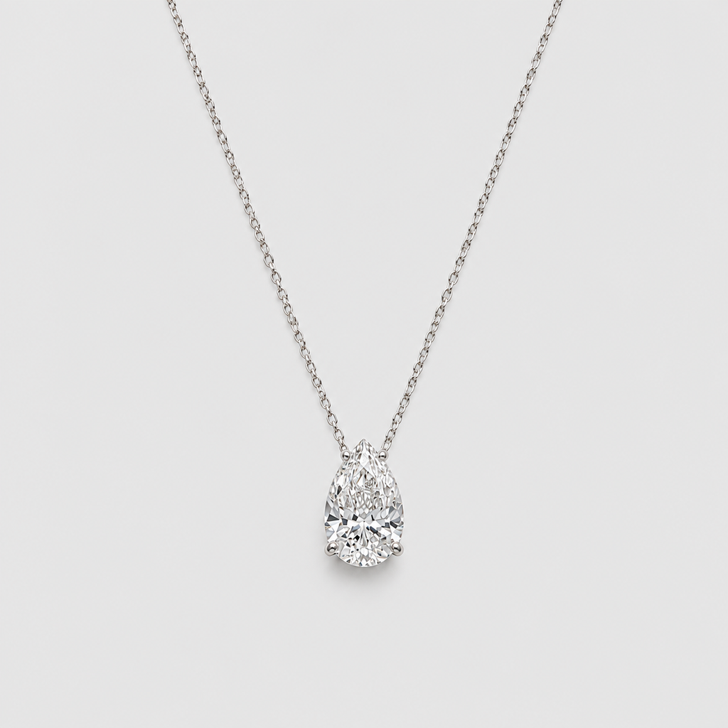 A pear-cut diamond pendant necklace on a delicate silver chain, set against a solid light gray background.