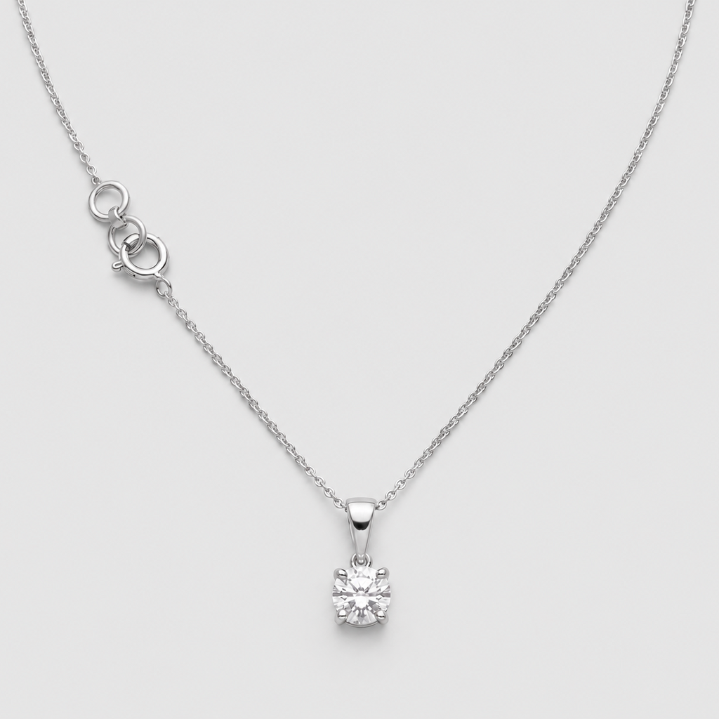 A delicate silver necklace with a single solitaire diamond pendant, displayed on a light gray background.
