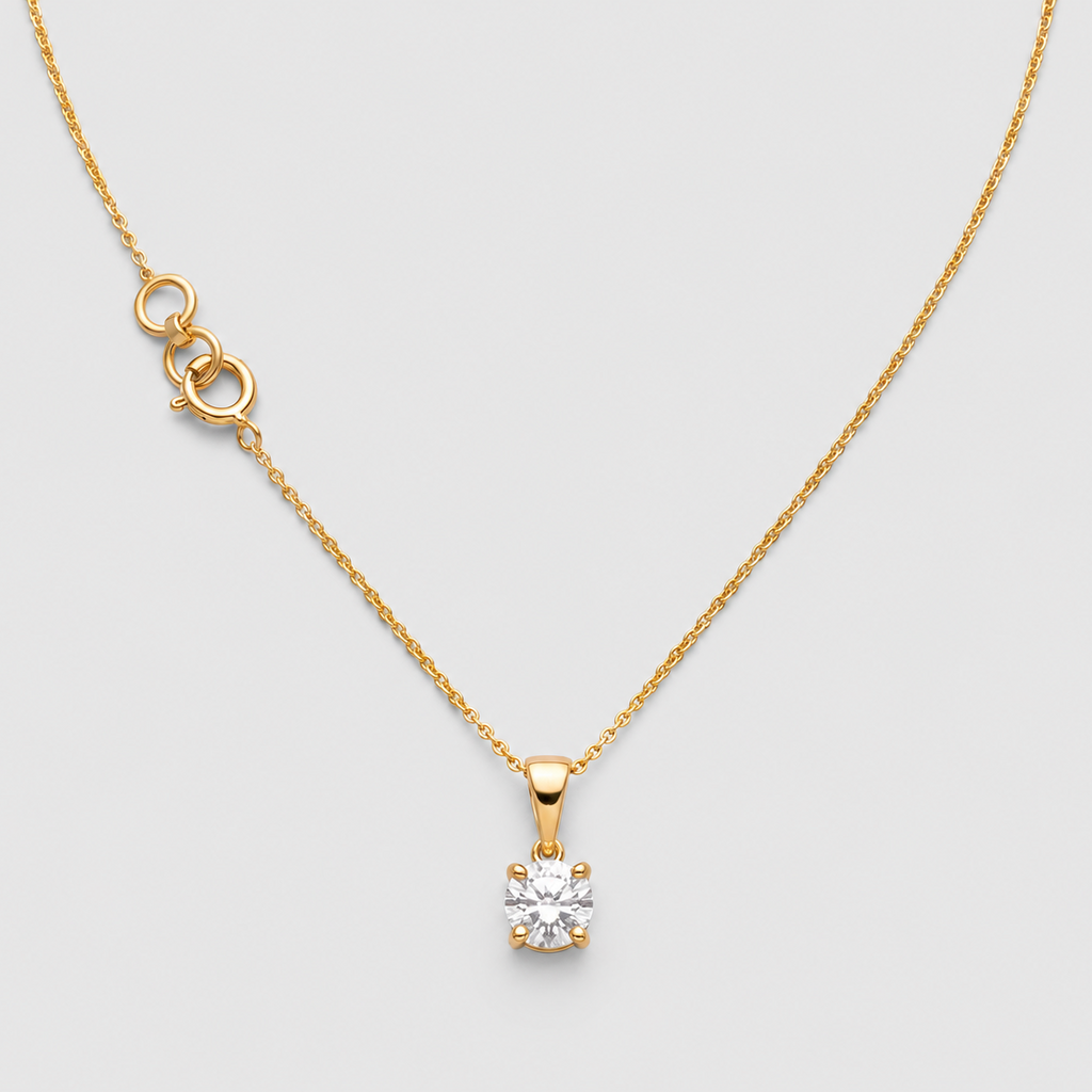A gold necklace with a delicate chain, a small gold extender clasp, and a single solitaire diamond pendant on a light gray background.