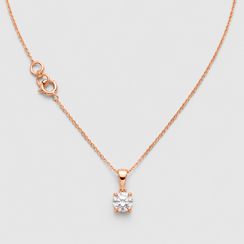 A delicate rose gold chain necklace with a small solitaire diamond pendant, displayed on a light gray background.