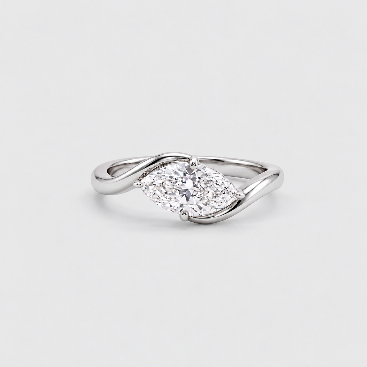A silver ring featuring a marquise-cut diamond center stone and smaller side stones, set on a twisted band, photographed on a light gray background.