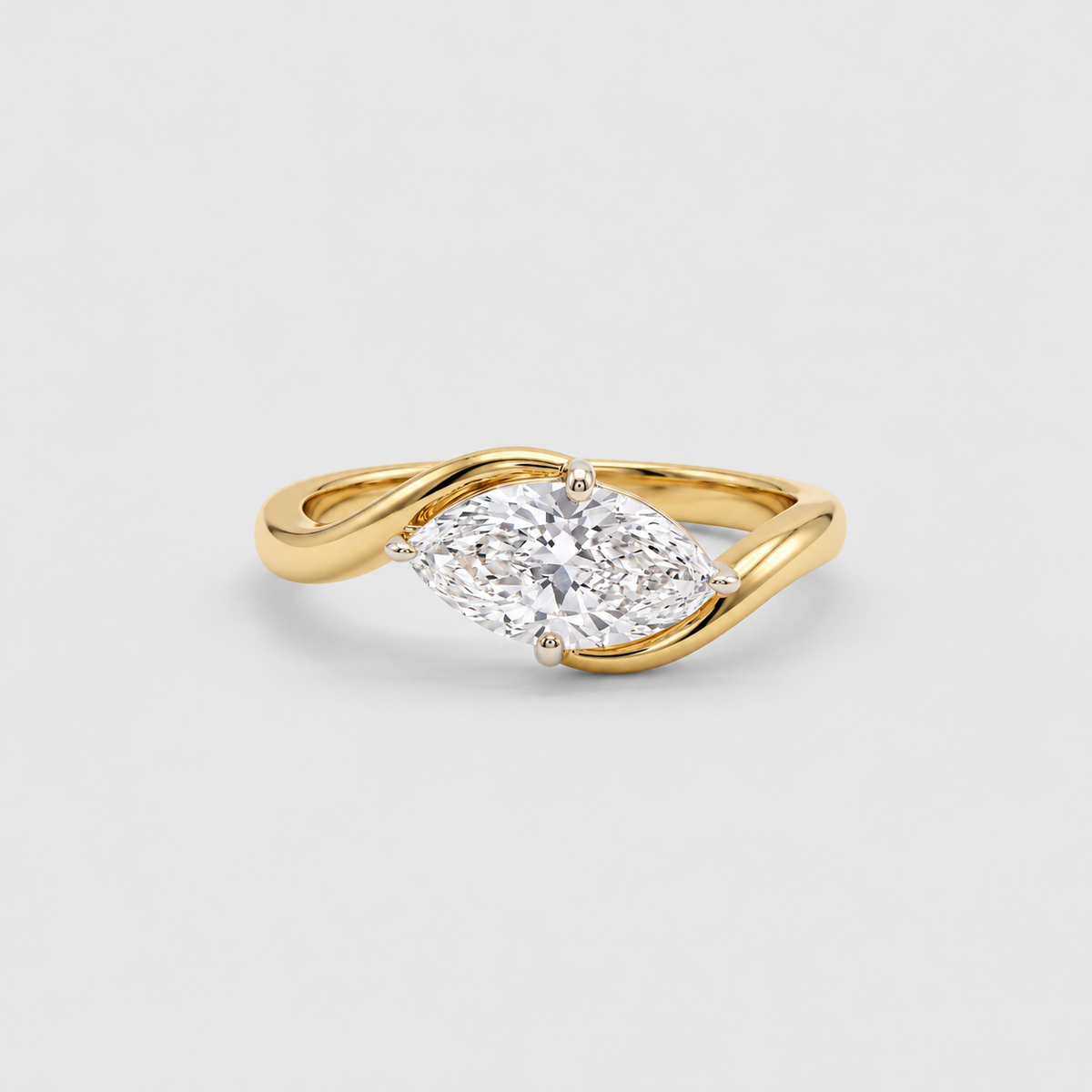 A yellow gold ring featuring a marquise-cut diamond set in a twisted band design, photographed on a clean light gray background.