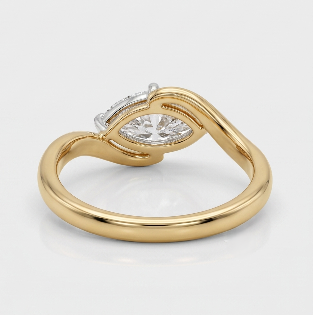 A yellow gold ring with a curved, intertwined band design and a central clear marquise-cut gemstone, shown on a clean light gray reflective surface.