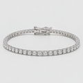 A tennis bracelet with a continuous row of round-cut clear stones in a silver-toned setting, featuring a clasp closure, shown on a light gray background.