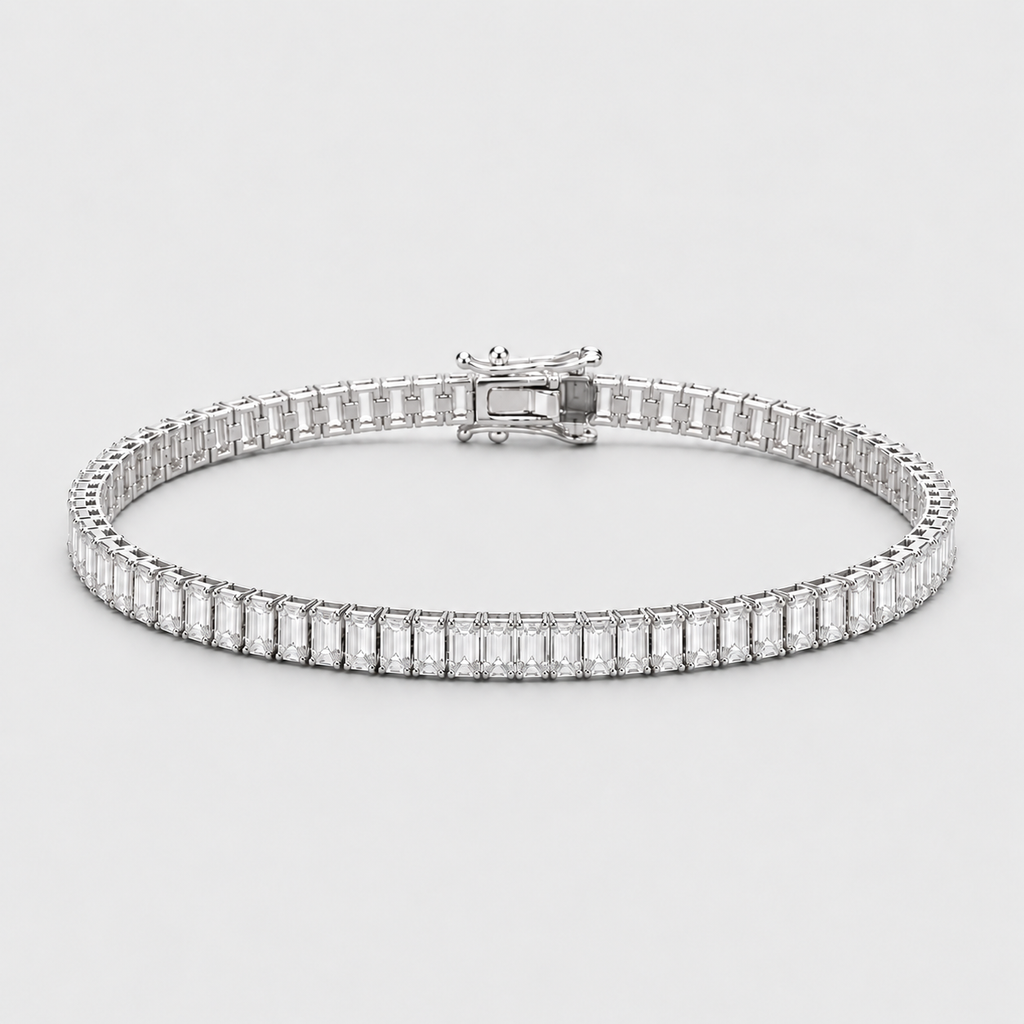 A silver tennis bracelet featuring a row of baguette-cut clear gemstones, displayed on a light gray background.
