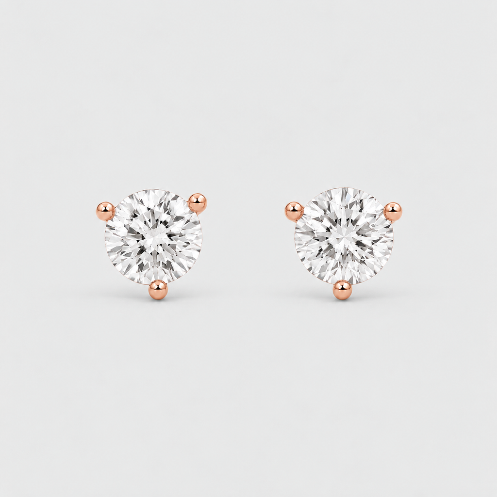 A pair of round-cut stud earrings with sparkling clear gemstones in three-prong rose gold settings, displayed on a clean light gray background.