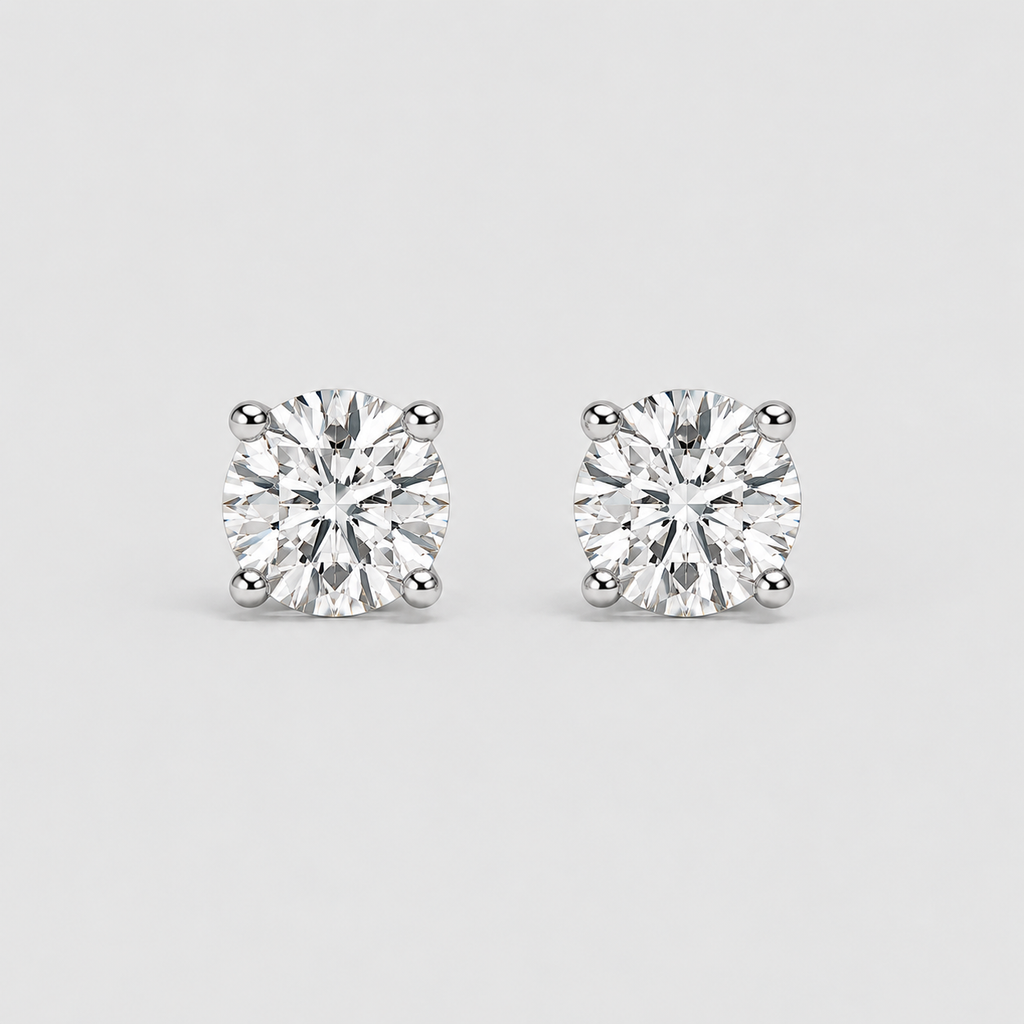 A pair of round brilliant-cut diamond stud earrings in a four-prong setting, shown on a light gray background.