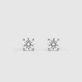 A pair of classic solitaire stud earrings featuring round brilliant-cut diamonds in four-prong settings, displayed on a clean, light gray background.