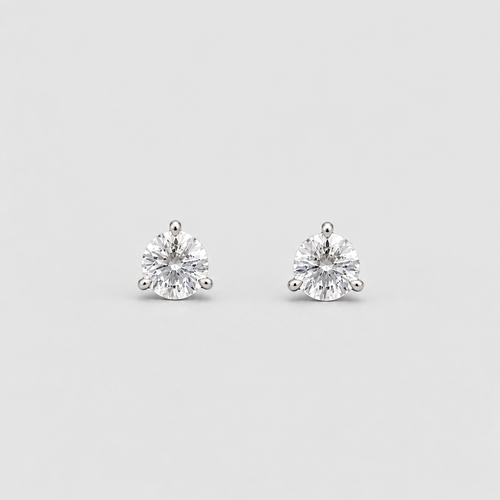 A pair of round-cut diamond stud earrings in a silver four-prong setting, displayed on a clean light gray background.