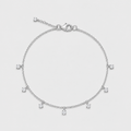 A delicate silver chain bracelet with seven small, clear, round-cut gemstone charms spaced evenly along the band, displayed on a light gray background.