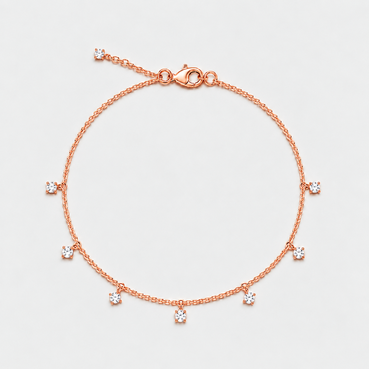 A delicate rose gold chain bracelet with a lobster clasp and five small bezel-set clear stones spaced along the chain, photographed on a clean light gray background.