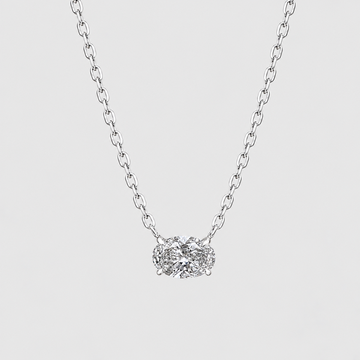 A silver chain necklace with a small, textured silver pendant set with clear gemstones, shown against a light gray background.
