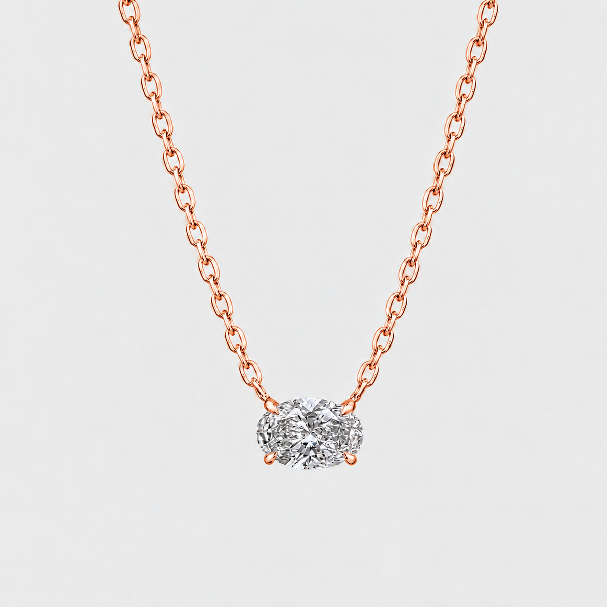 A delicate rose gold chain necklace with a small cluster of clear gemstones in a silver-toned setting, displayed against a light gray background.