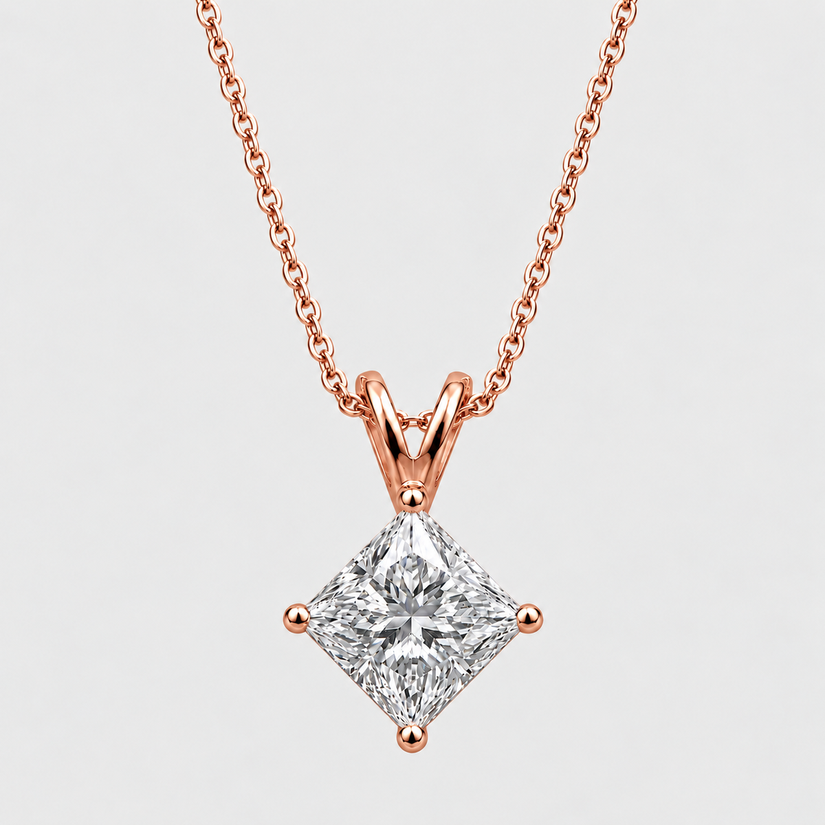 A rose gold necklace with a princess-cut diamond pendant, shown against a light gray background.