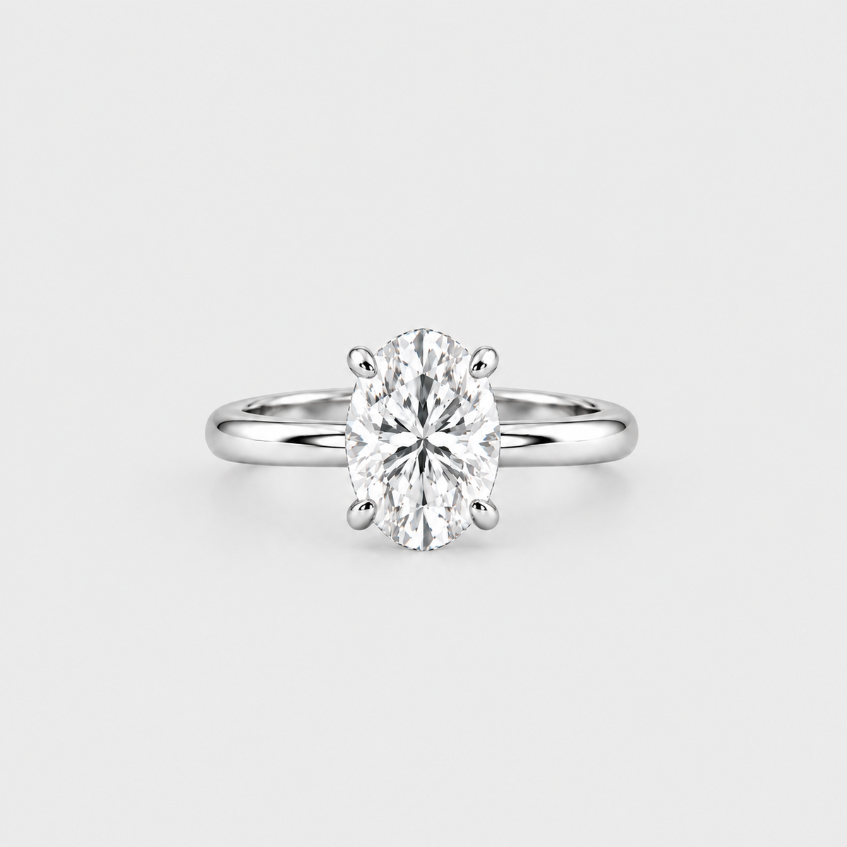 An oval-cut diamond engagement ring with a polished silver-colored band, set against a clean, light gray background.