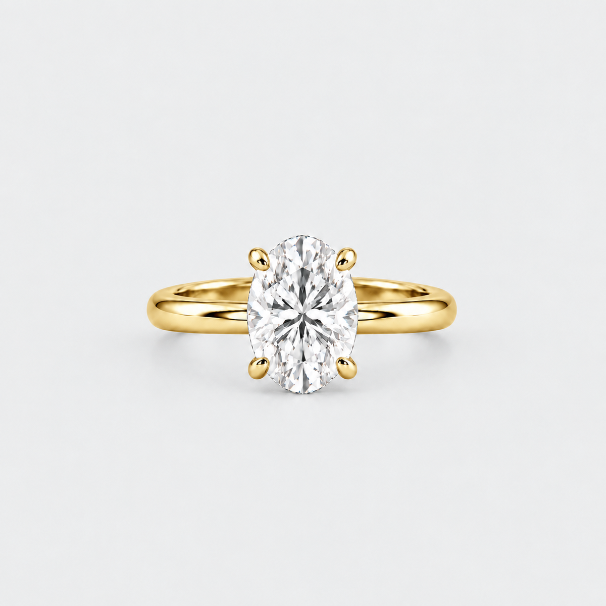 An oval-cut diamond engagement ring with a yellow gold band, set against a clean light gray background.