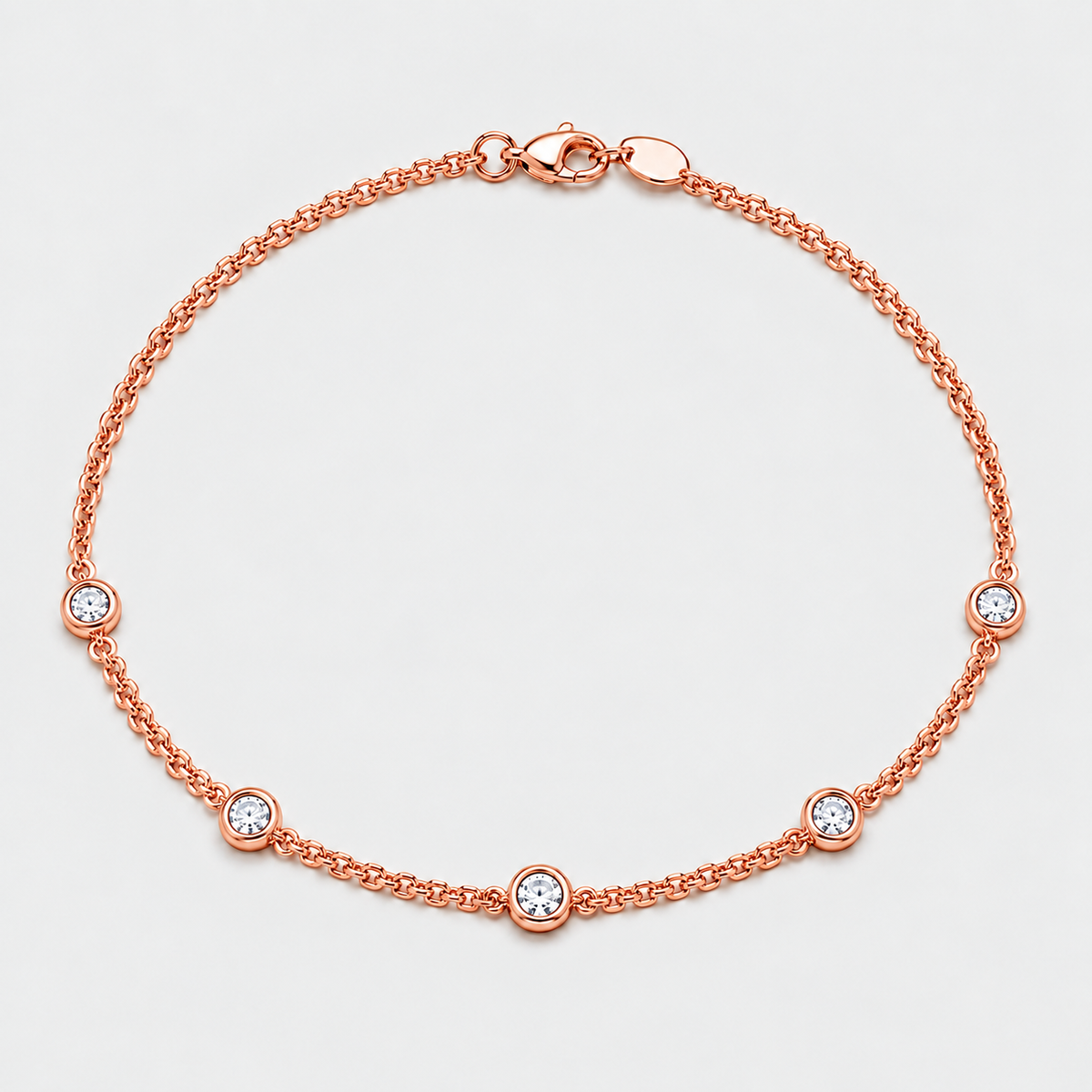 A rose gold chain anklet with five bezel-set clear round stones, displayed on a light gray background.