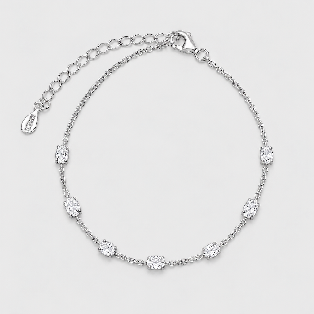 A silver chain bracelet with seven oval-cut clear stones spaced evenly along the band, featuring an adjustable lobster clasp and extension chain with a small engraved tag that reads VVD.