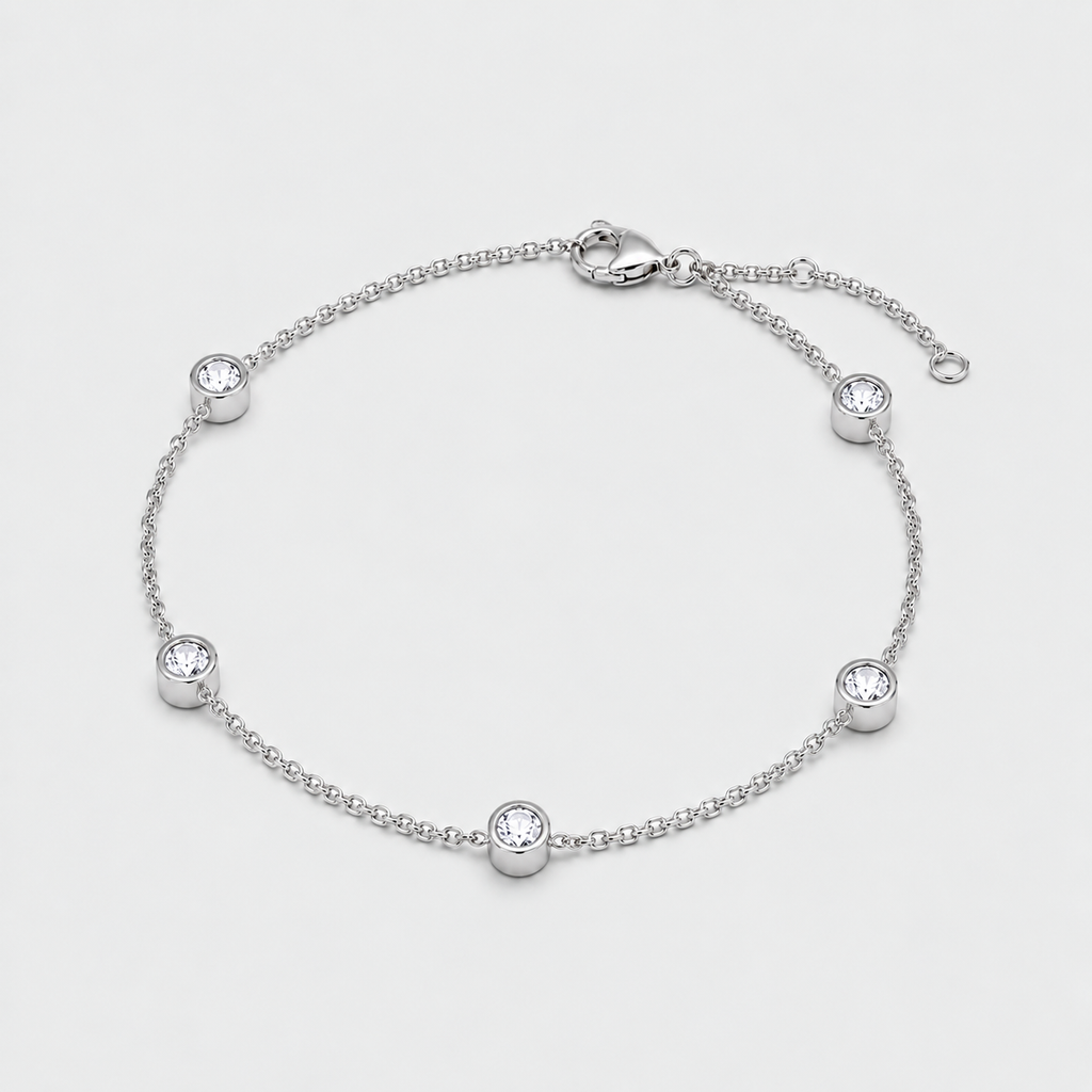 A silver chain anklet with five bezel-set clear round stones, displayed on a light gray background.