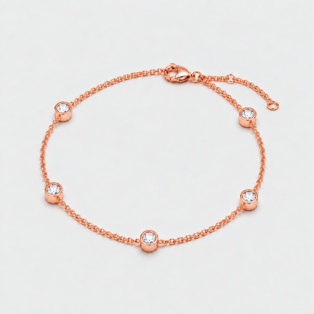 A delicate rose gold chain bracelet with five bezel-set clear round gemstones, displayed on a clean light gray background.