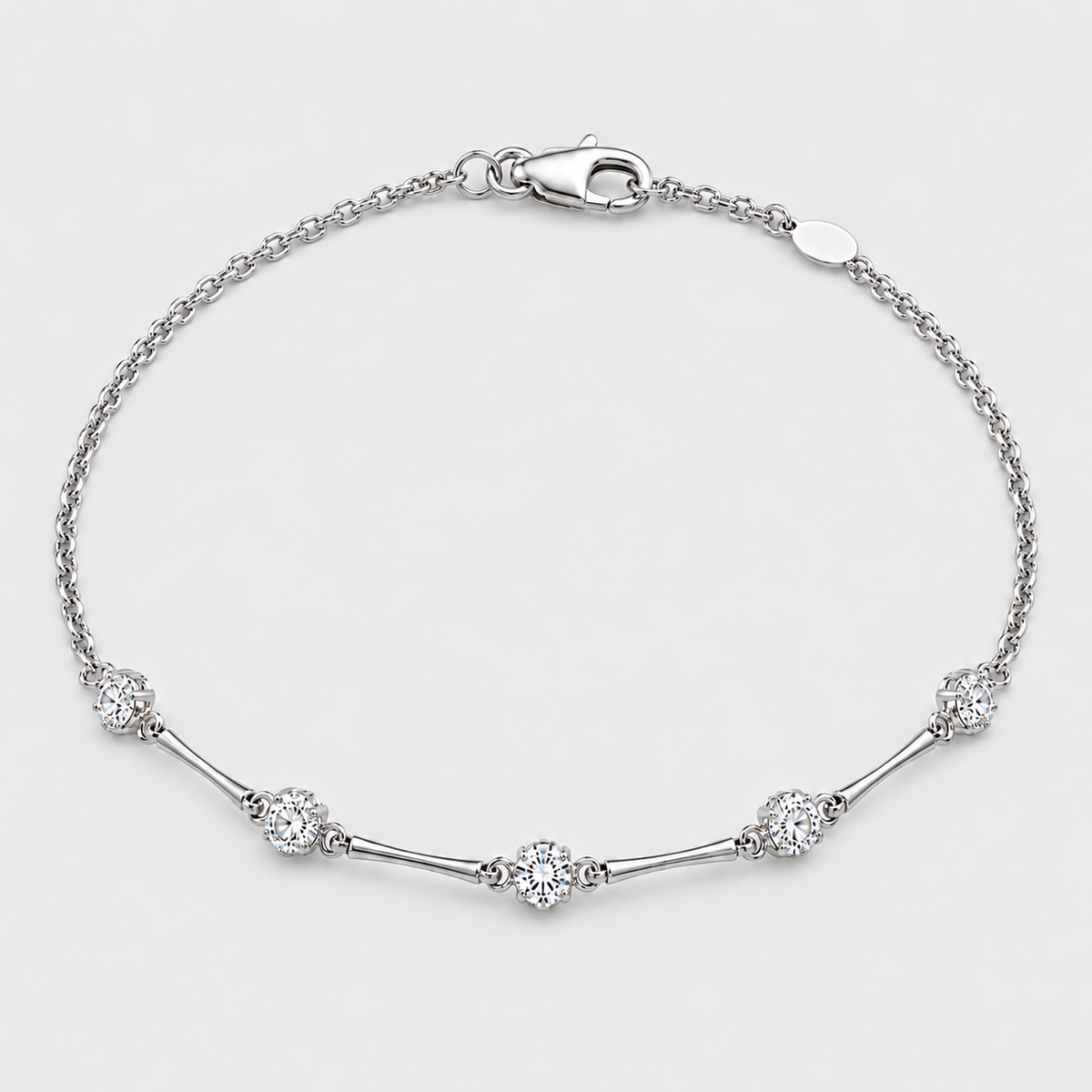 A silver chain bracelet with a lobster clasp, featuring five clear round-cut and oval pavé diamonds spaced along the chain, set against a clean light gray background.