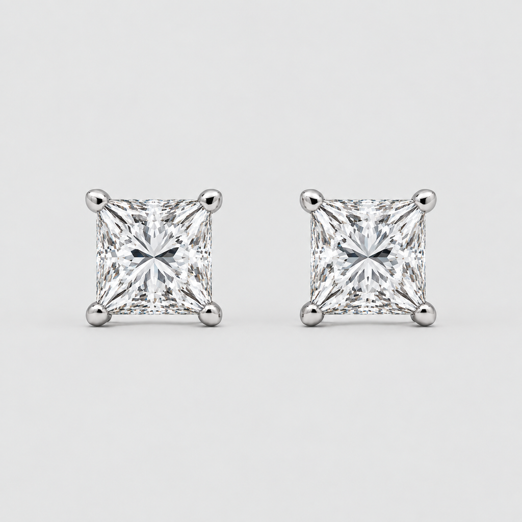 A pair of princess-cut diamond stud earrings in a silver four-prong setting, displayed on a clean light gray background.