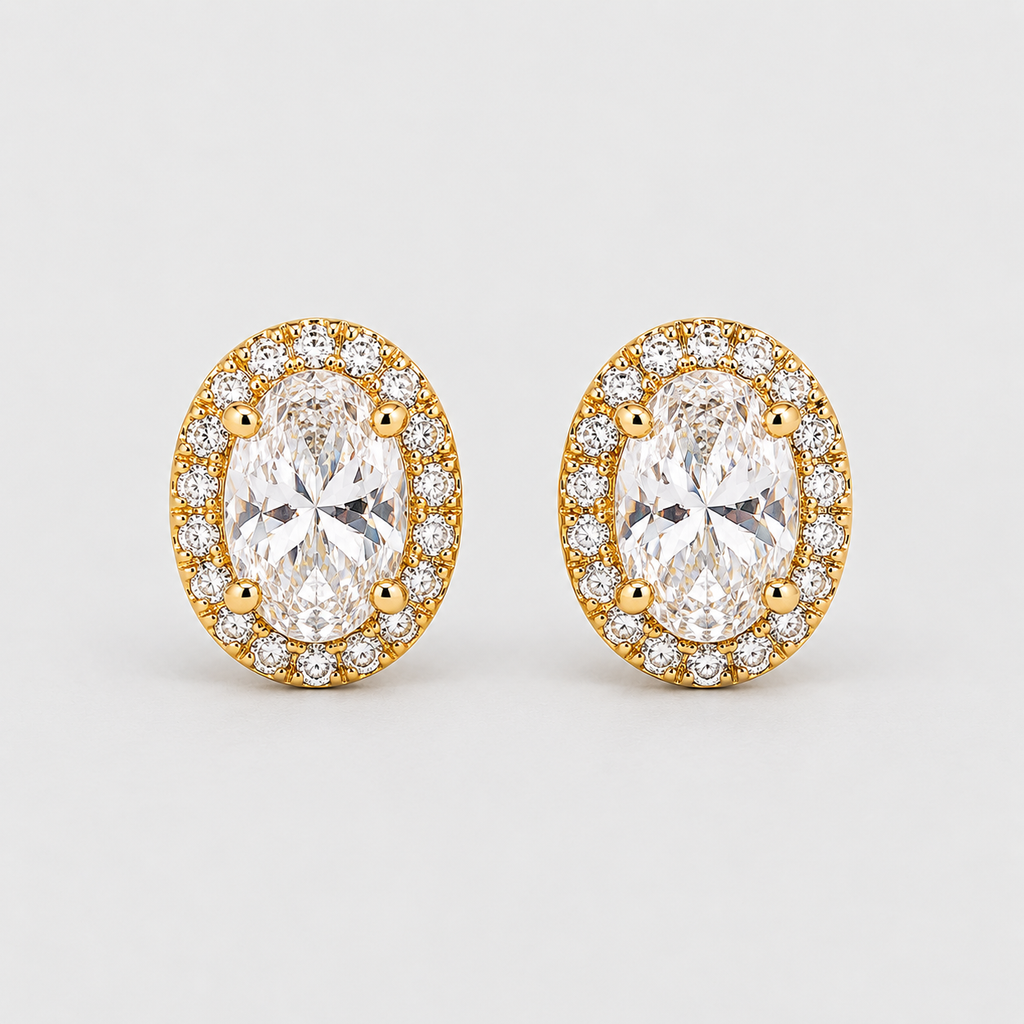 A pair of oval stud earrings featuring large clear marquise-cut center stones surrounded by a halo of smaller round clear stones in yellow gold settings, photographed on a light gray background.