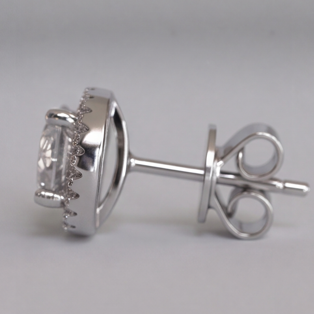 A silver-toned stud earring with a large clear oval gemstone surrounded by small sparkling accents, shown from the side on a light gray background.