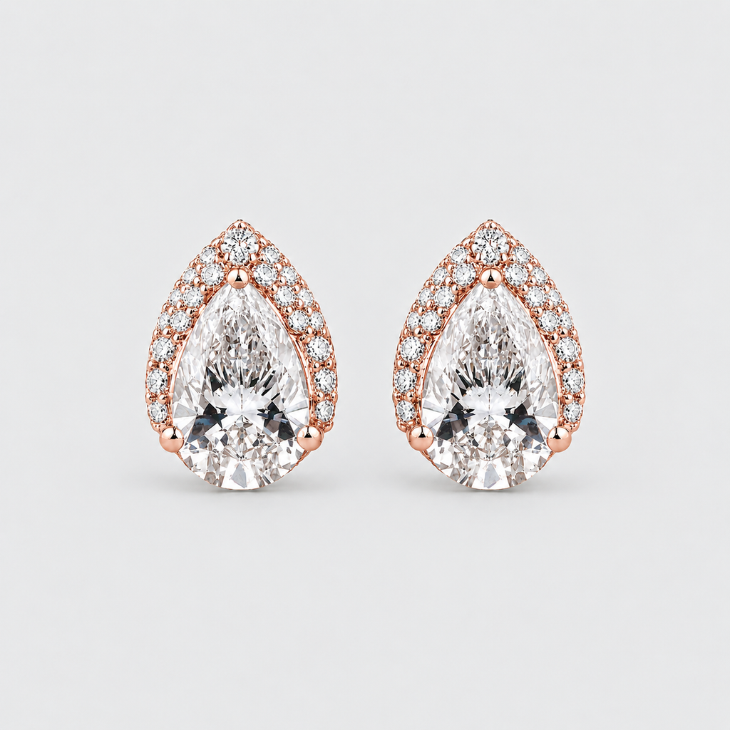 A pair of pear-shaped rose gold stud earrings with clear gemstones, set against a light gray background.