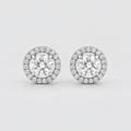 A pair of round halo stud earrings featuring a central round-cut clear gemstone surrounded by a halo of smaller clear stones in a silver-toned setting, shown on a light gray background.