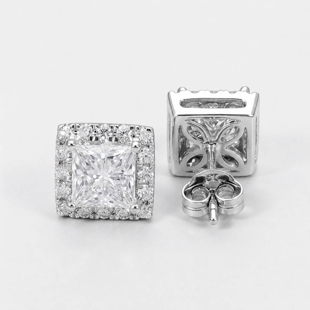 A pair of silver-toned stud earrings with a square princess-cut center stone surrounded by a halo of small clear stones, shown on a clean white background. One earring is facing forward to show the front design, and the other is turned to show the back setting.