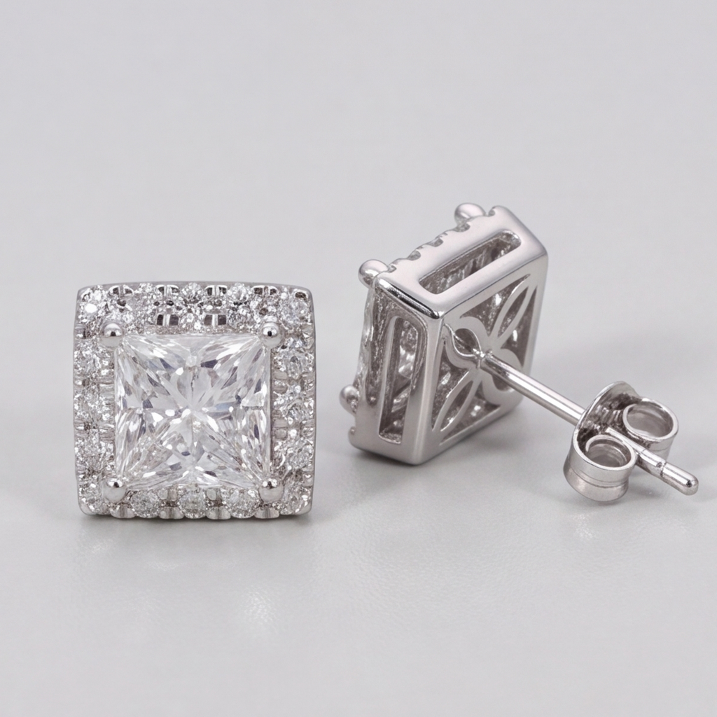 A pair of square halo stud earrings in silver-tone metal, featuring a princess-cut clear center stone surrounded by a halo of smaller round stones, with one earring shown from the front and the other from the side/back.