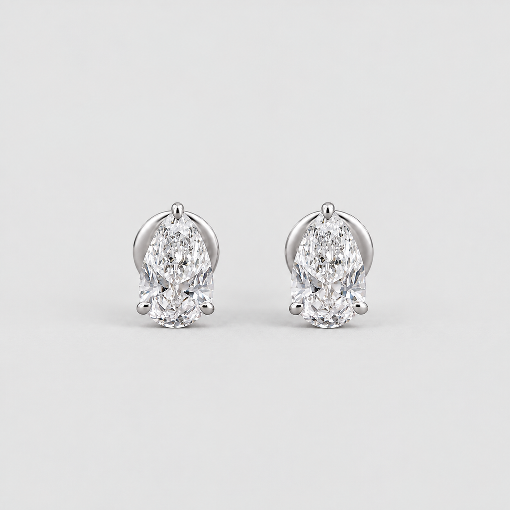 A pair of pear-cut diamond stud earrings in a silver-tone setting, displayed on a clean light gray background.